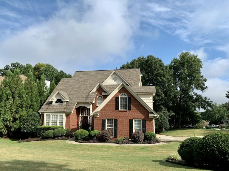 Classic brick two-story home with black shutters and mature trees in a Middle Tennessee neighborhood