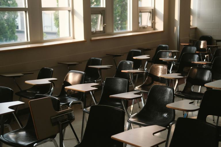 Empty public school classroom with tablet-arm desks in warm late afternoon light, a reminder that school zoning drives home searches across Middle Tennessee