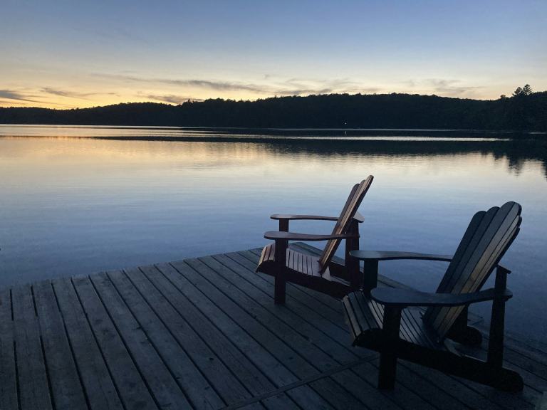 Two Adirondack chairs on a wooden dock overlooking a calm lake at dusk, the kind of evening lake life Hendersonville residents enjoy on Old Hickory Lake